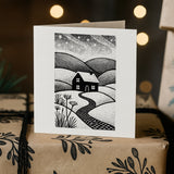 Greeting card with a black and white landscape illustration on a wrapped gift box.