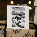 Greeting card with a black and white landscape illustration on a wrapped gift box.