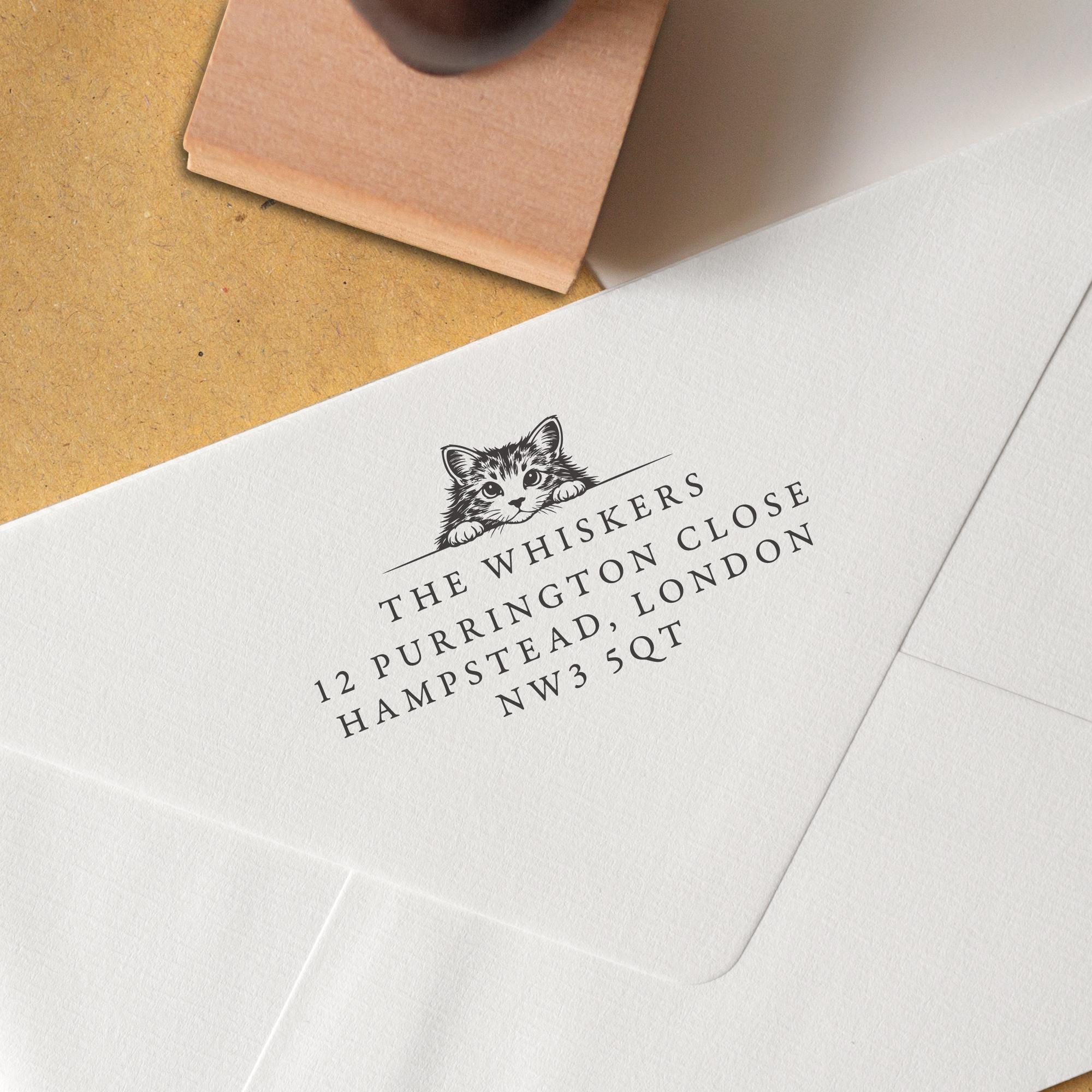 This Cat Address Stamp features a detailed black-and-white illustration of a cat peeking over a wall and personalised address details stamped onto an envelope.