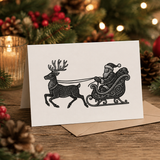 Christmas card with Santa and reindeer illustration on a wooden table with festive decorations.