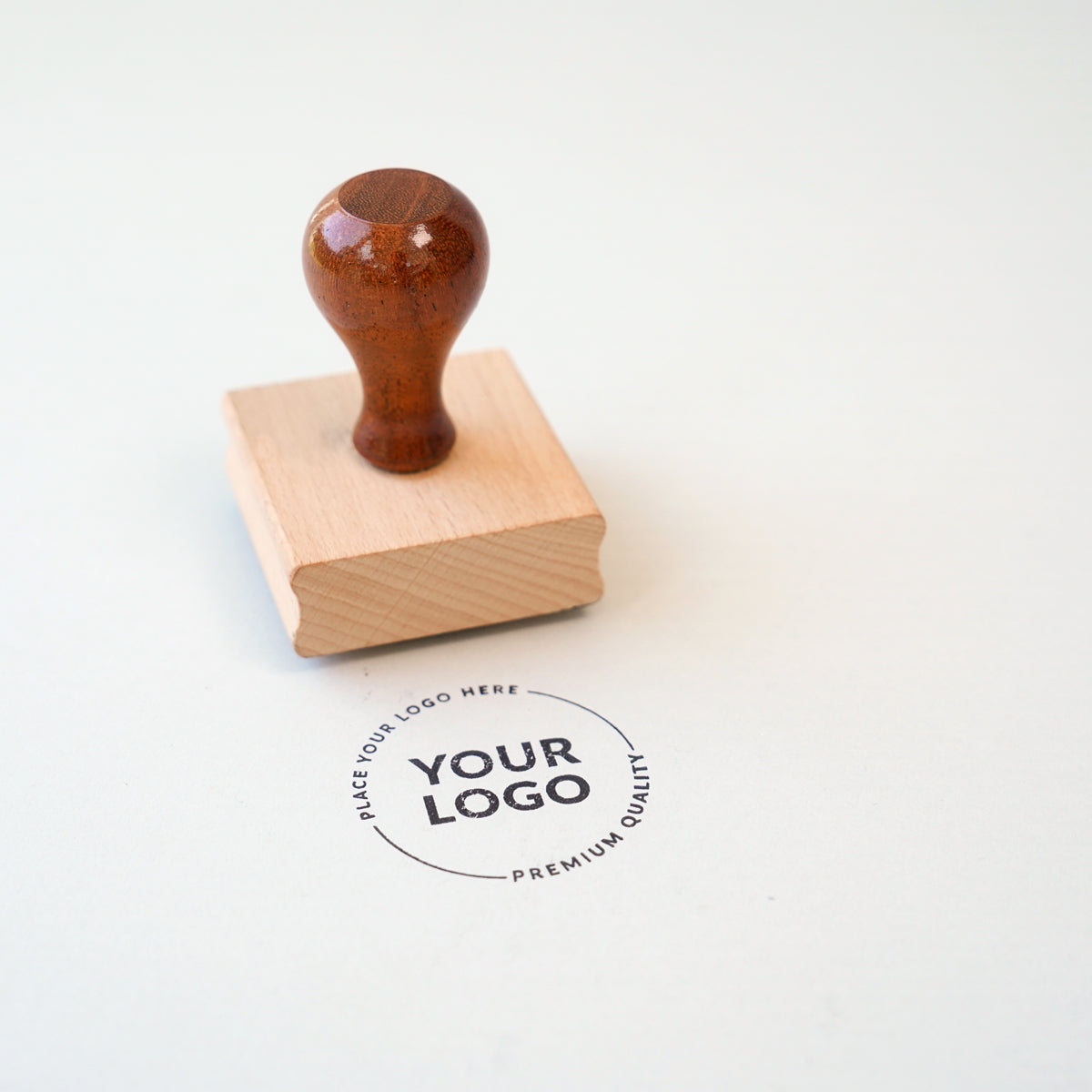 A custom rubber stamp with a wooden handle, making a stamp imprint on paper 