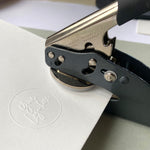 Handheld embosser seal creating a custom logo impression on white card