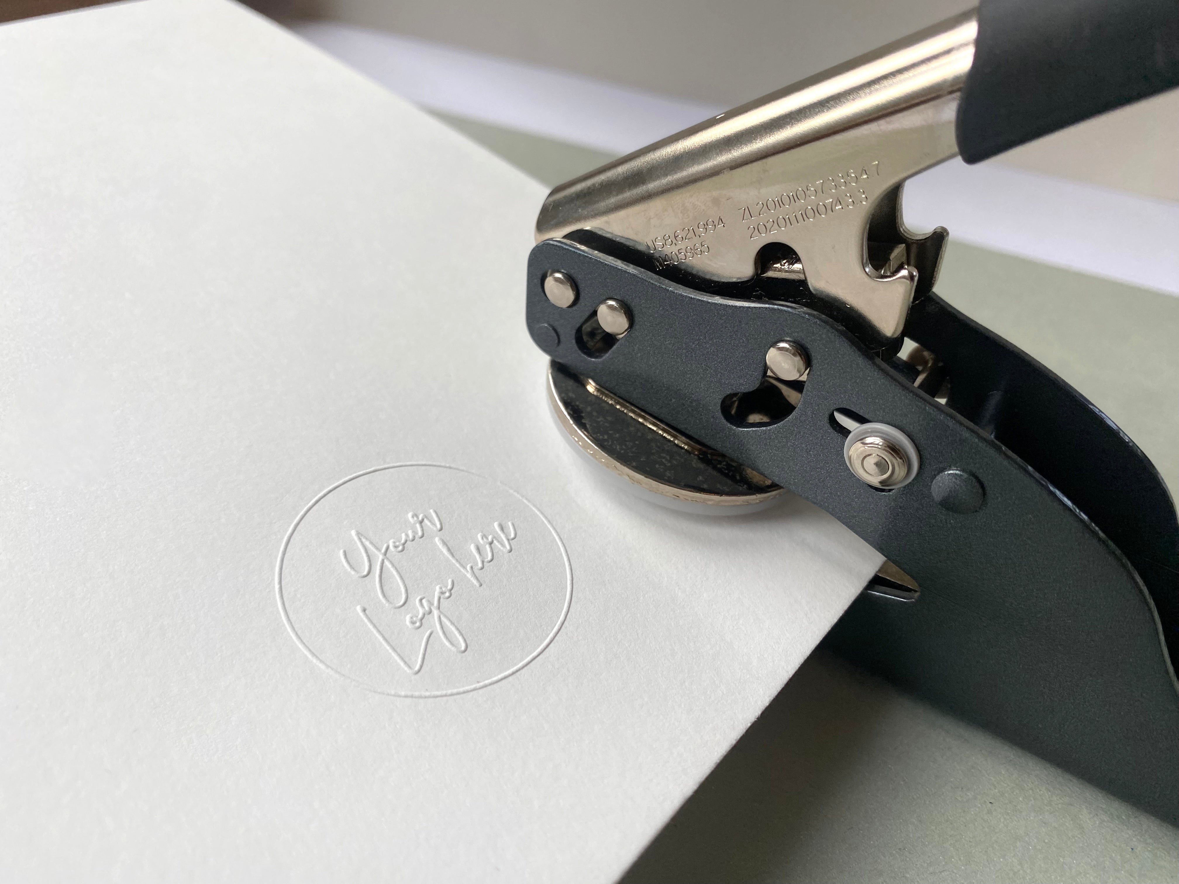 Custom Logo Embosser leaving a raised impression onto plain white paper
