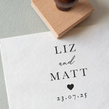 Personalised wooden wedding stamp with couple’s names, date and heart, stamped on white textured paper
