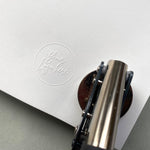 Personalised logo embossing stamp pressed into luxury white paper