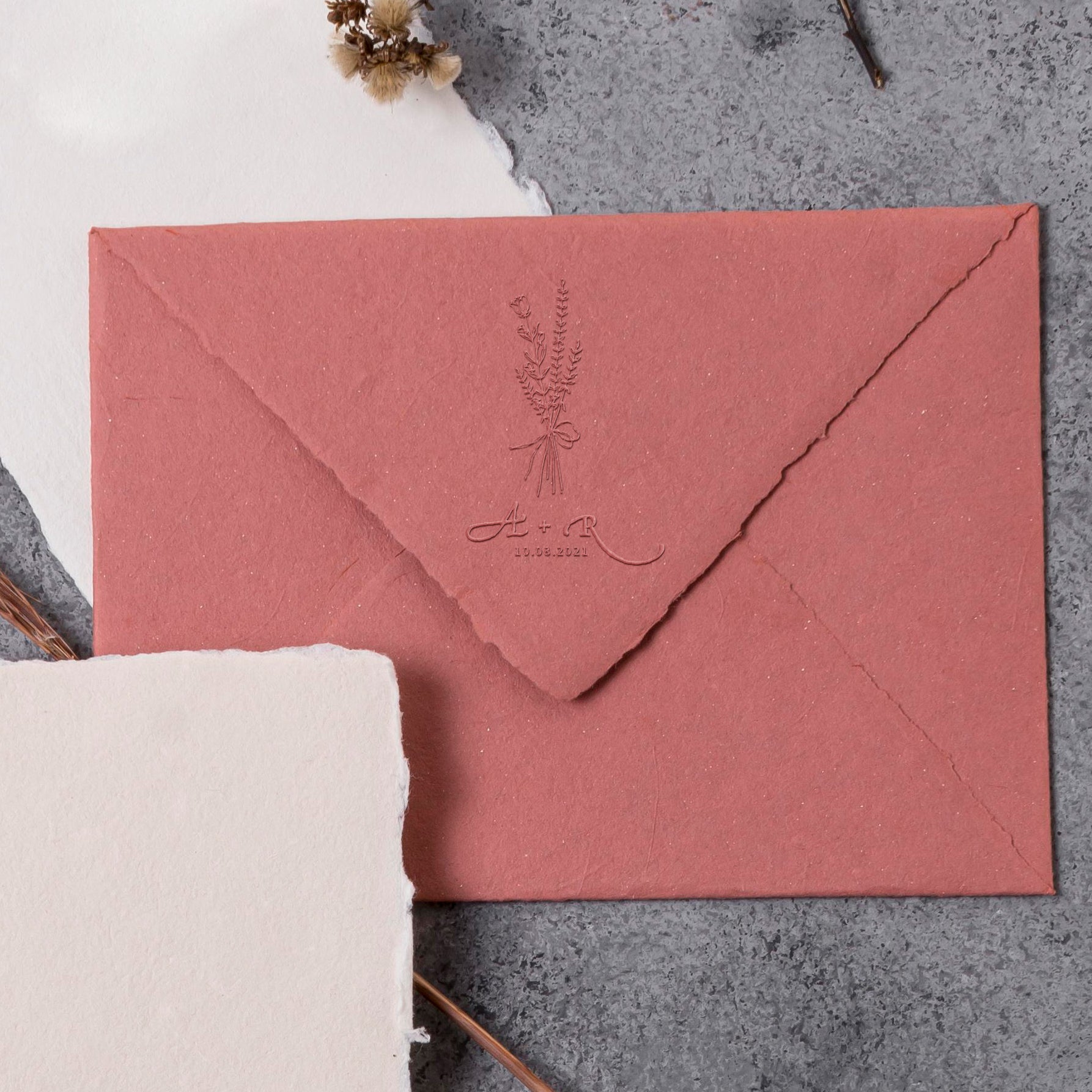 Wedding embosser with wildflower, couple's initials and wedding date embossed on a high quality pink envelope with ruffled edges