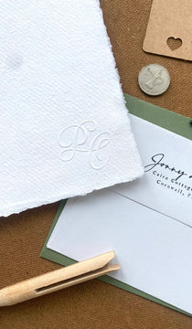 Close-up of wedding stationery with embossed initials.