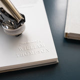Classic book embosser with traditional font pressed into the page of a book