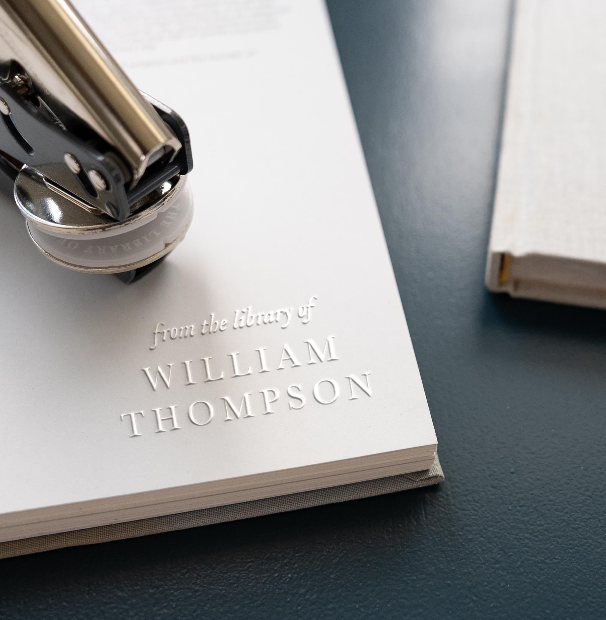Classic book embosser with traditional font pressed into the page of a book