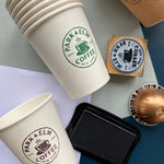 Stack of paper coffee cups with custom branding stamped onto the cups with a rubber stamp 