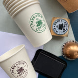 Stack of paper coffee cups with custom branding stamped onto the cups with a rubber stamp 