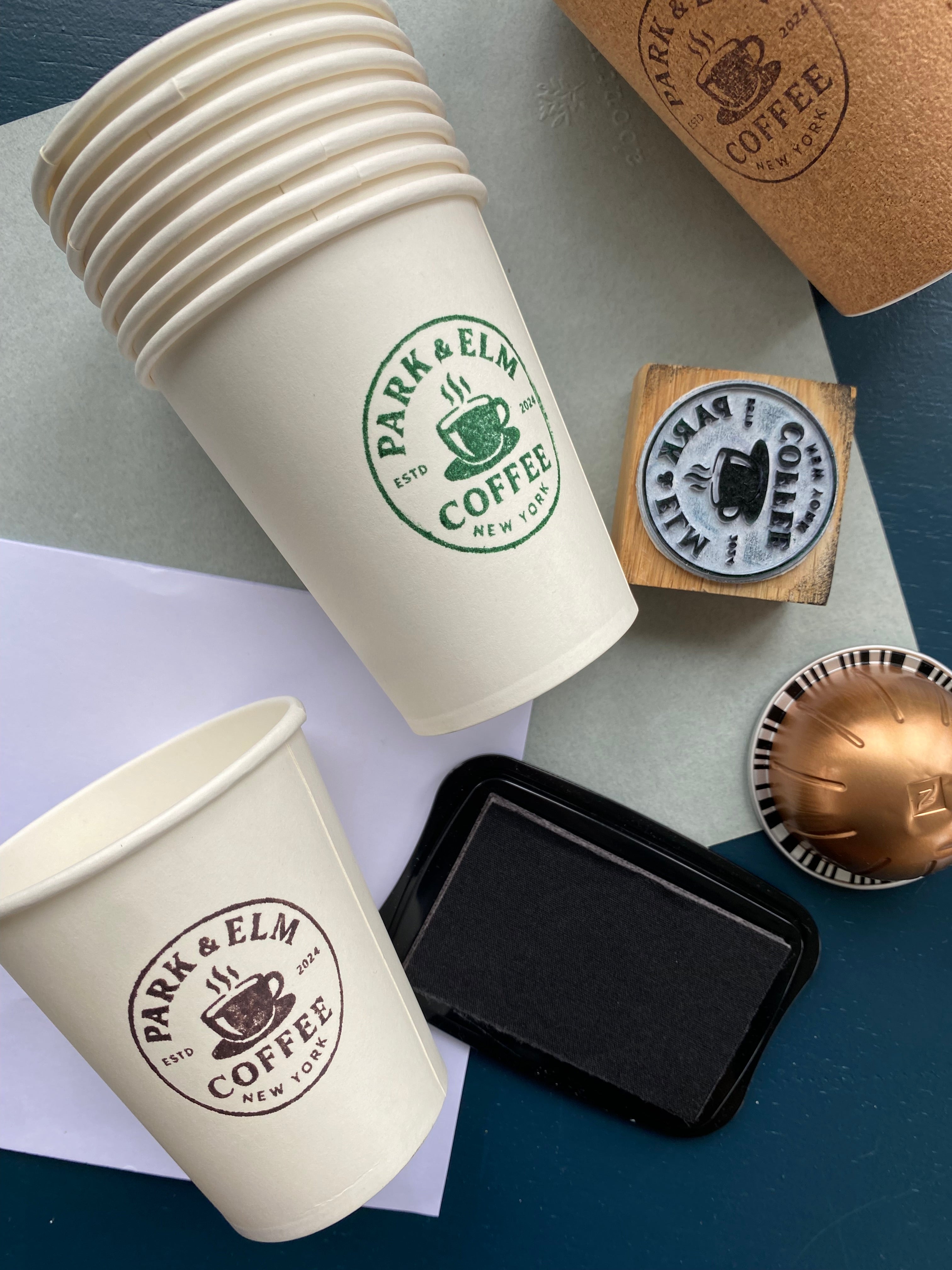 Stack of paper coffee cups with custom branding stamped onto the cups with a rubber stamp 
