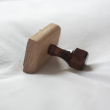Wooden rubber stamp with a wooden handle on a white cotton background