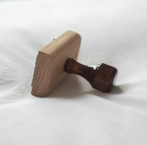 Wooden rubber stamp with a wooden handle on a white cotton background