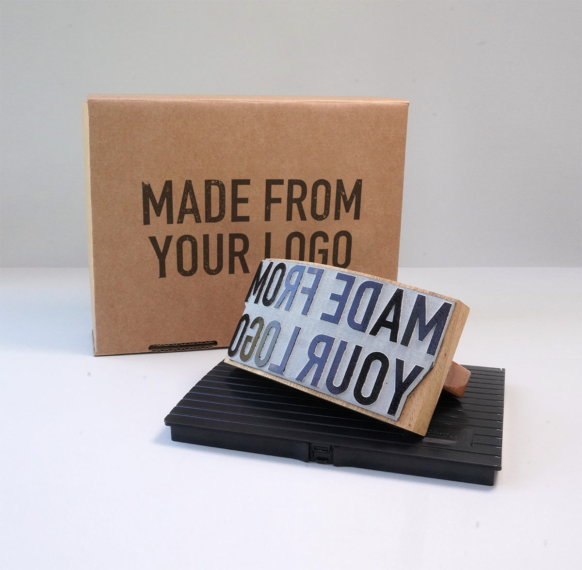 A large custom packaging rubber stamp with ink pad, showing the rocker handle and custom wording against a neutral background.