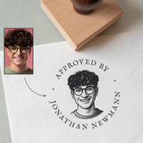 custom rubber portrait stamp with a stamped portrait illustration and 'the wording Approved by Jonathan Newman'  on a paper surface.