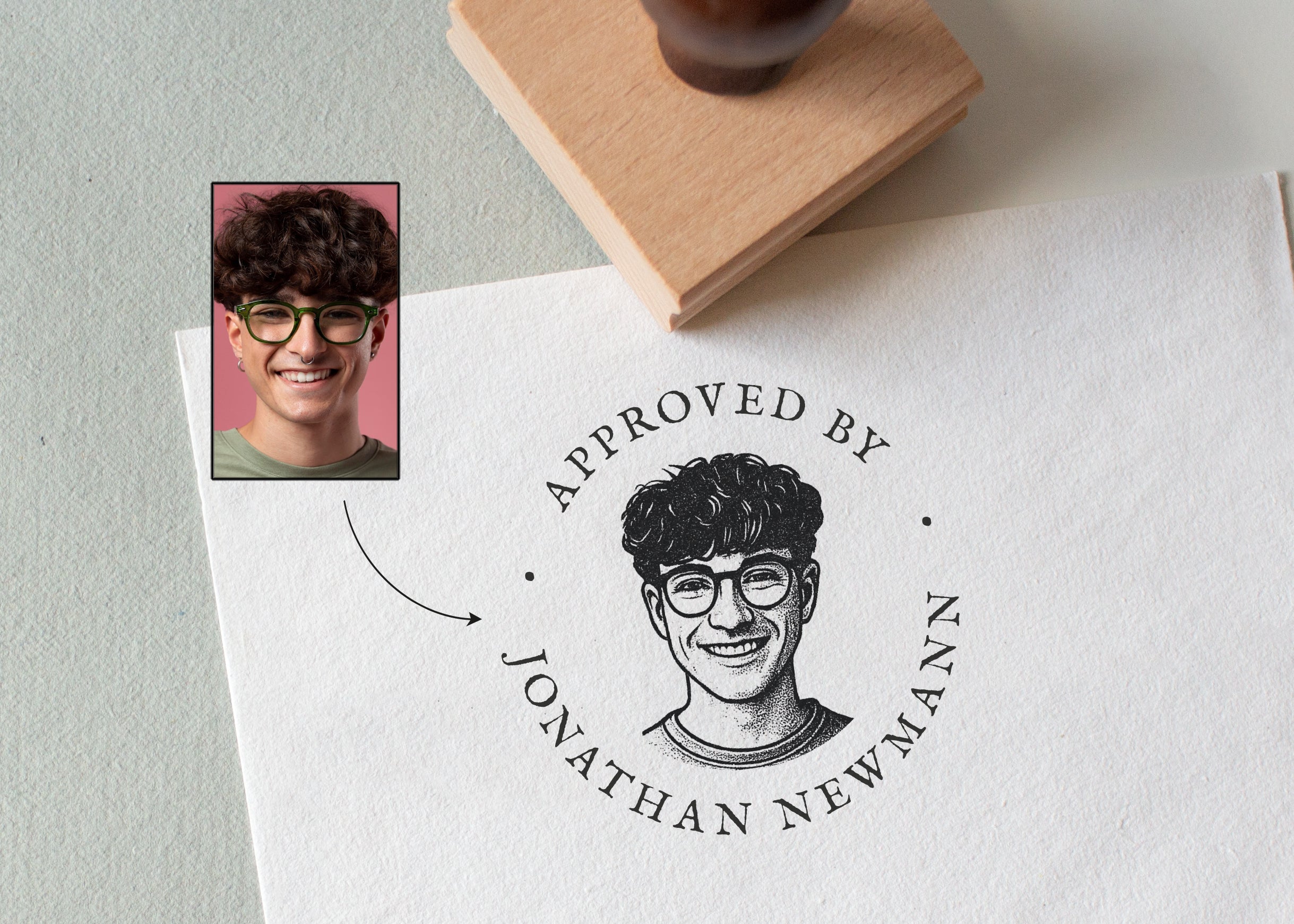 custom rubber portrait stamp with a stamped portrait illustration and 'the wording Approved by Jonathan Newman'  on a paper surface.