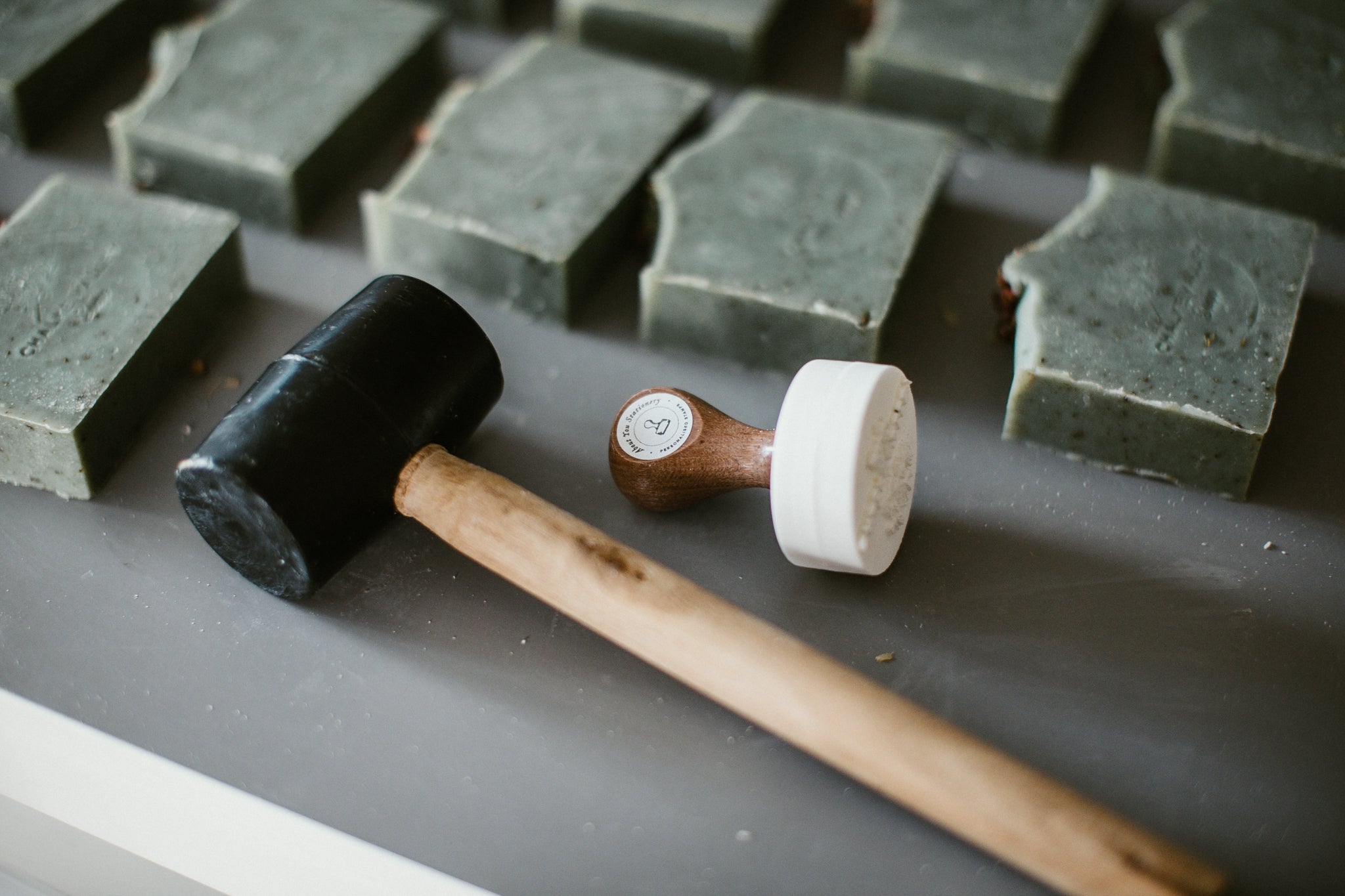 custom soap stamp from About You stationery laying next to soap bars with impressed logos 