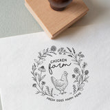 Decorative stamp with chicken illustration, wildflowers and custom text stamped on to a white textured paper