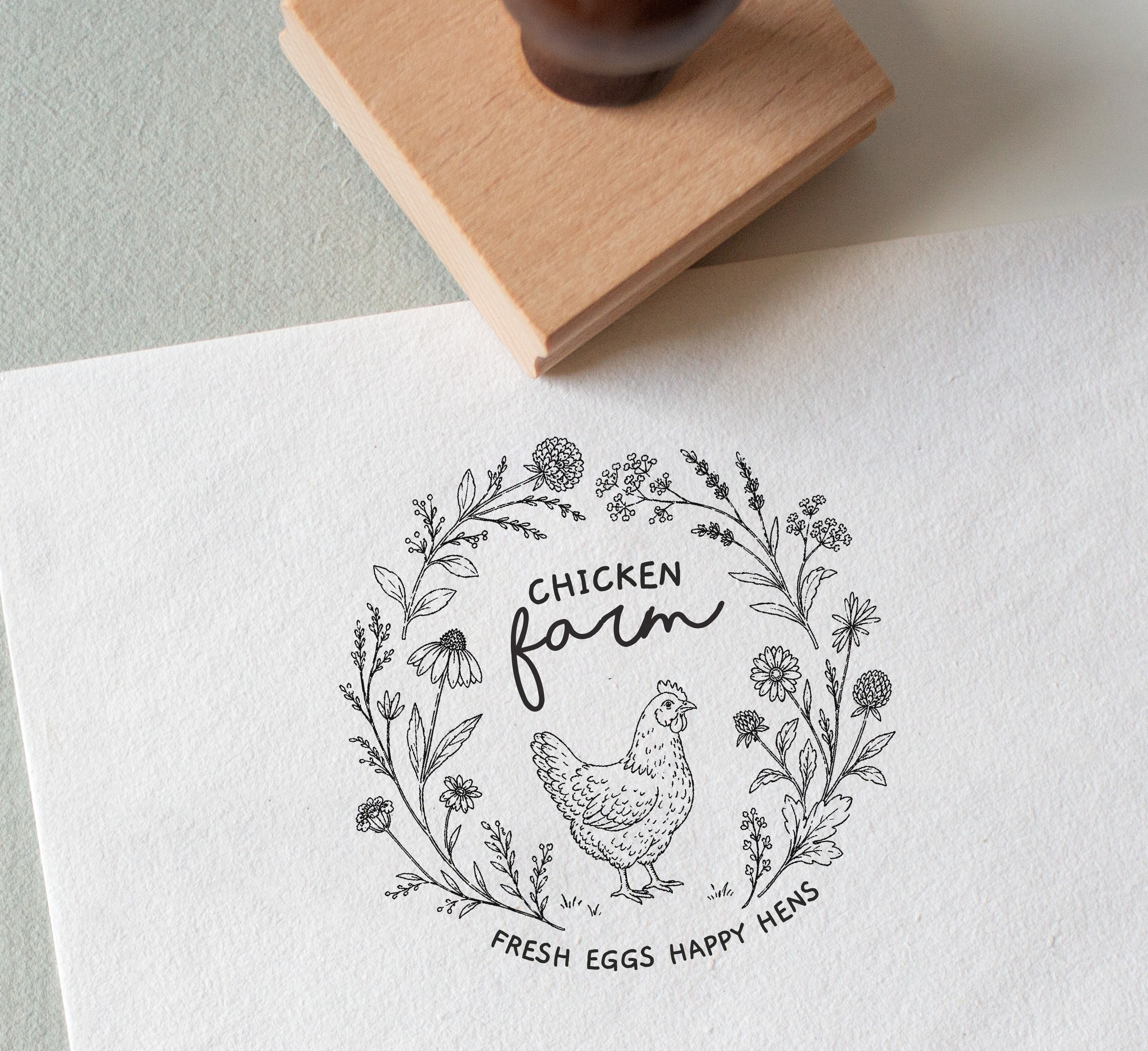 Decorative stamp with chicken illustration, wildflowers and custom text stamped on to a white textured paper