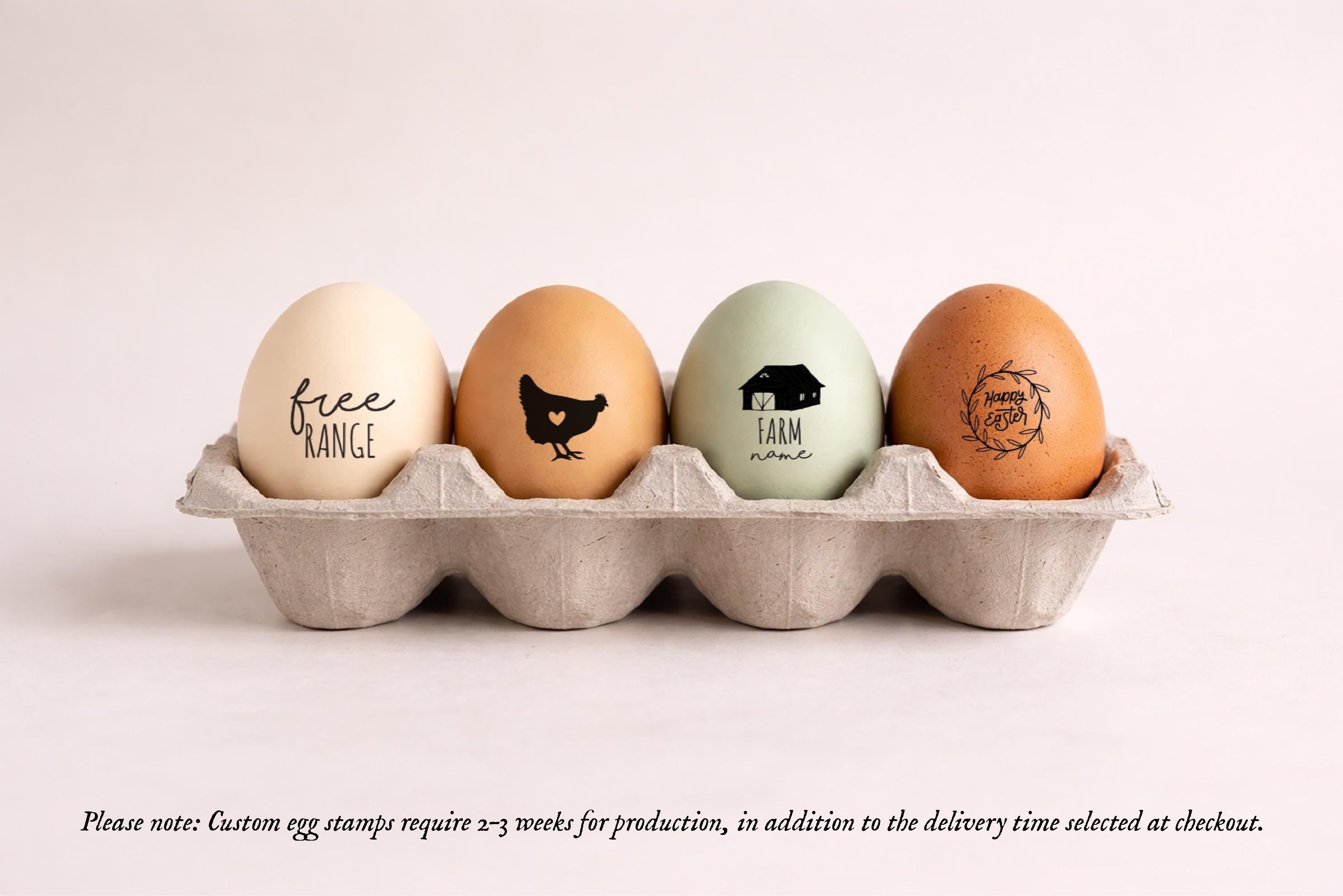 Four decorative eggs in a gray paper egg carton on a light beige background. The eggs are decorated with black custom stamps including 'free RANGE', a chicken silhouette, 'FARM life', and a floral wreath.