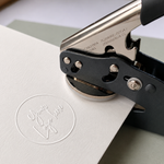 Handheld embosser seal creating a custom logo impression on white card