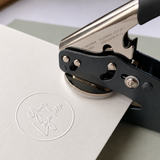 Handheld embosser seal creating a custom logo impression on white card