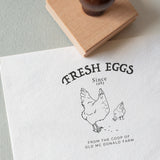 'Fresh Eggs' stamped on textured paper with it's wooden rubber stamp displayed next to it