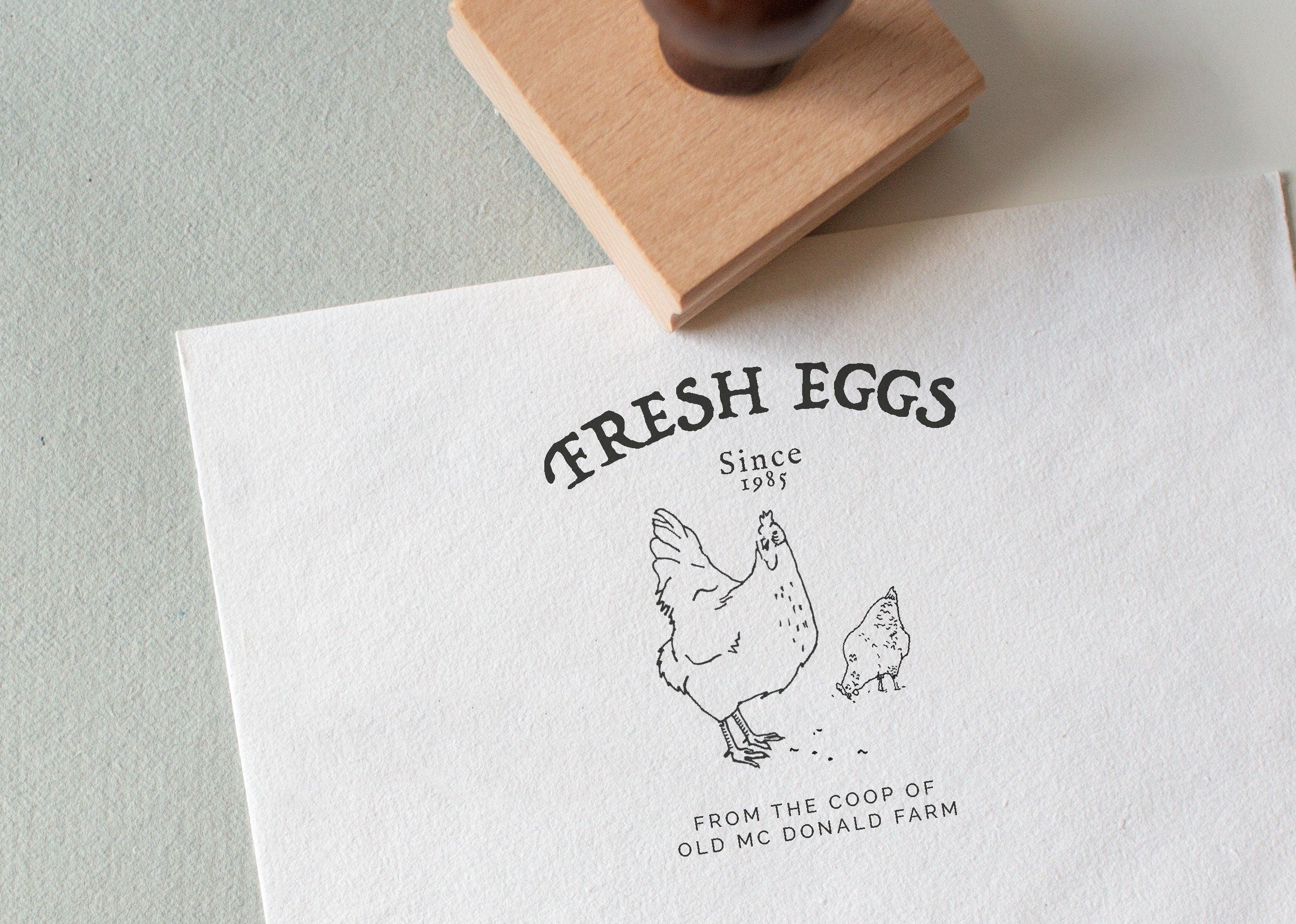 'Fresh Eggs' stamped on textured paper with it's wooden rubber stamp displayed next to it