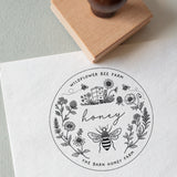 Round honey label with bee and floral design stamped on a white card, and with custom text