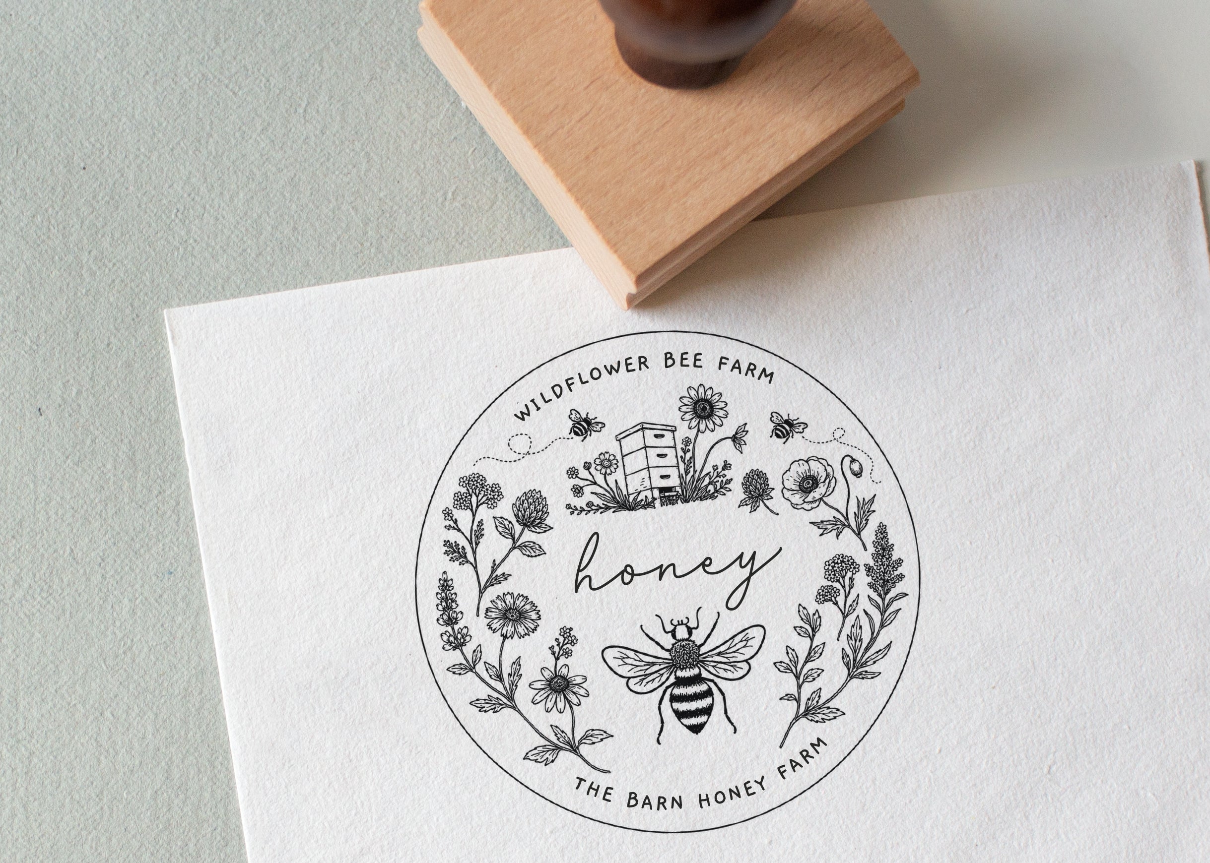 Round honey label with bee and floral design stamped on a white card, and with custom text