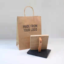Kraft paper bag with 'MADE FROM YOUR LOGO' text and a large custom rubber stamp on a white background
