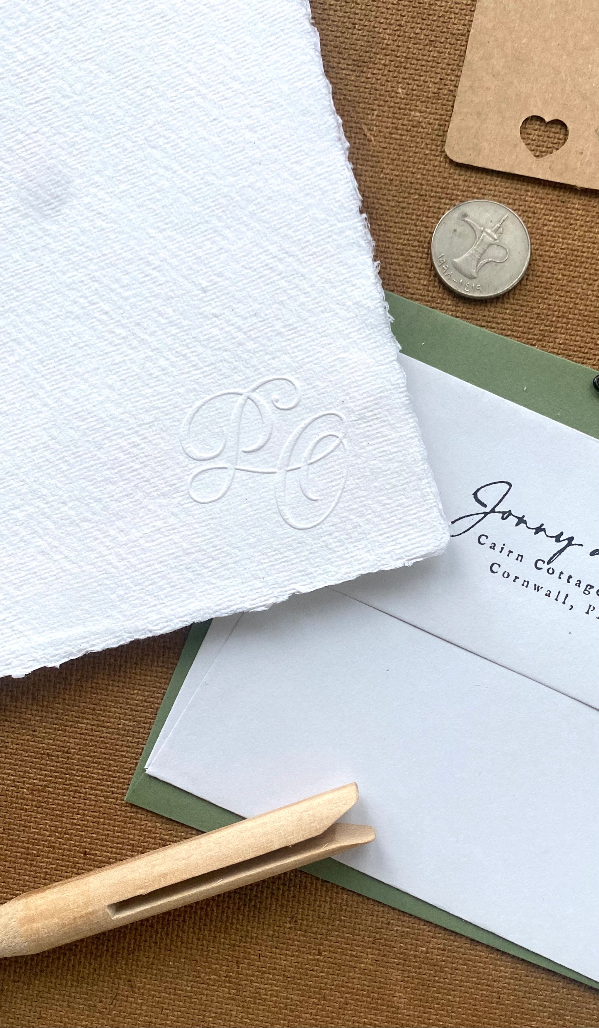 Close-up of wedding stationery with modern embossed initials in a calligraphic style.