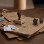 Wooden stamp with custom wording stamped onto a brown paper bag