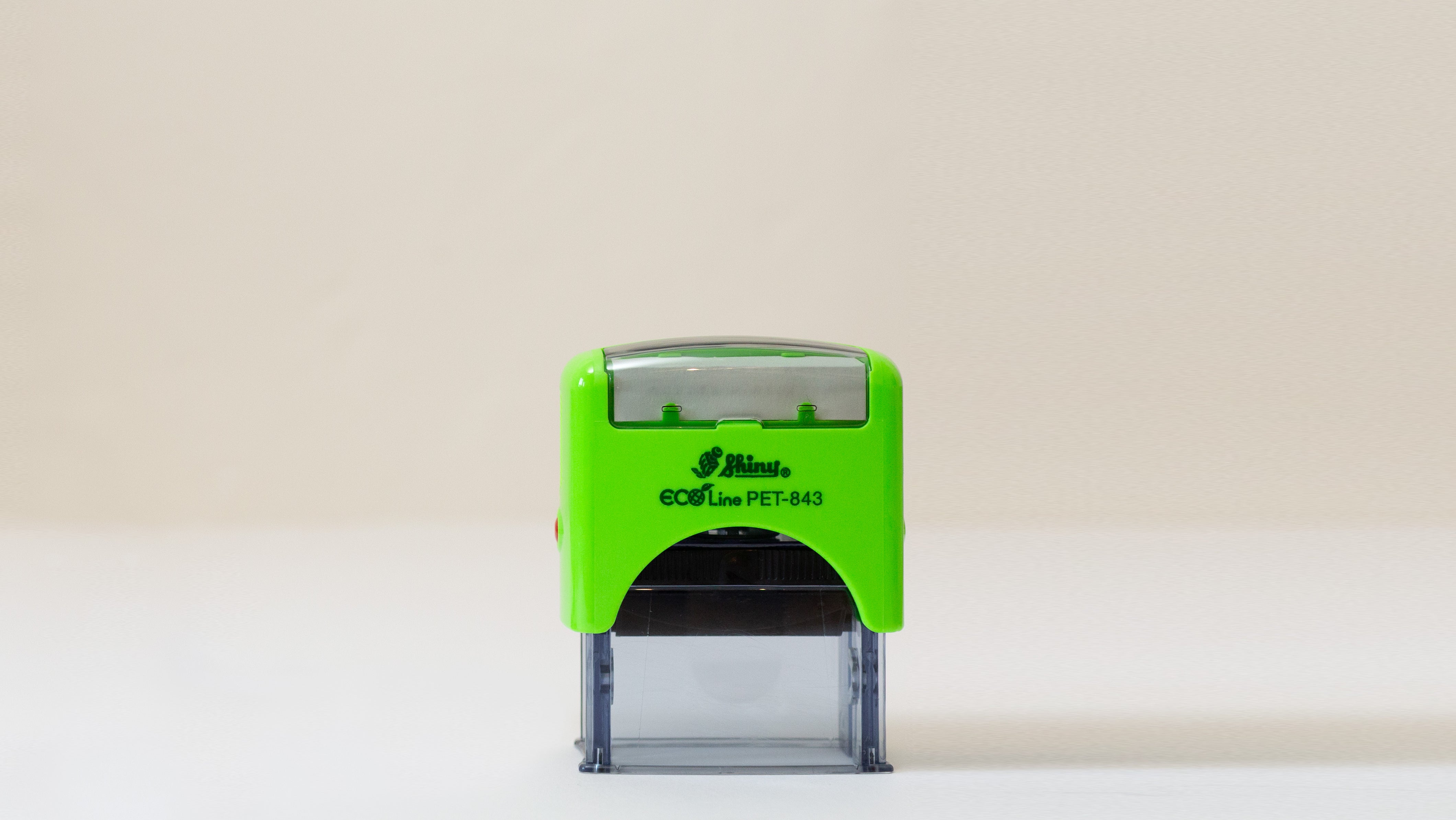 Video featuring an eco-friendly, green,  self-inking logo stamp stamping a logo with the wording 'your logo here' onto brown kraft paper