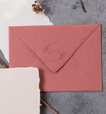 traditional monogram embosser with floral wreath  design embossed onto a red high-quality wedding envelope 