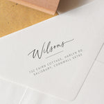 A close-up image of a custom handwritten address stamp on an envelope, showing the engraved return address in a stylish script.