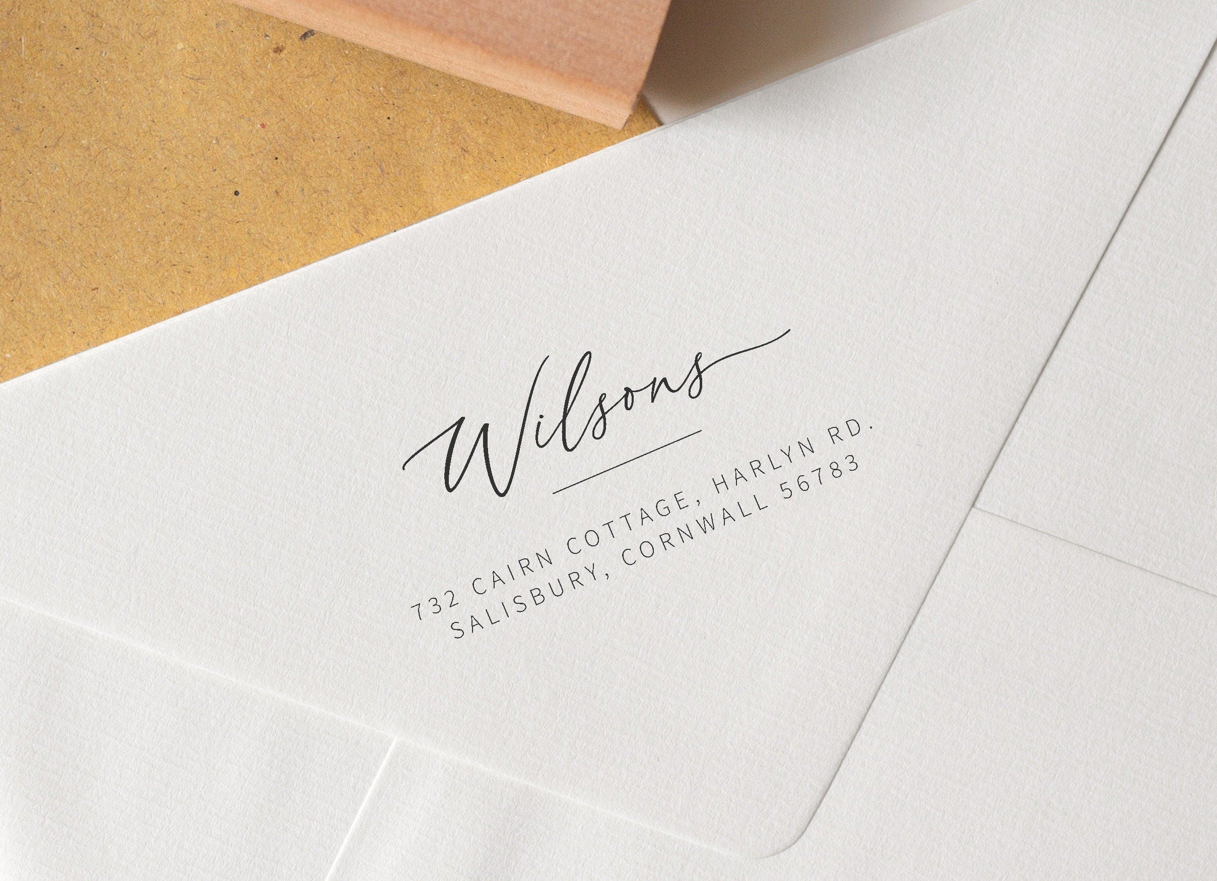A close-up image of a custom handwritten address stamp on an envelope, showing the engraved return address in a stylish script.