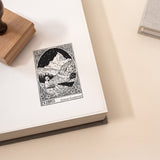 Beautiful custom rubber book stamp showing a young person playing a flute in a mountain scene, stamped on the right page of an open book