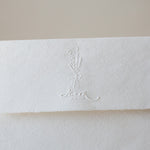 Floral couple initials wedding embosser impression on a handmade wedding envelope.