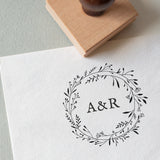 A personalized floral wreath stamp with initials 'AR' in the centre.
