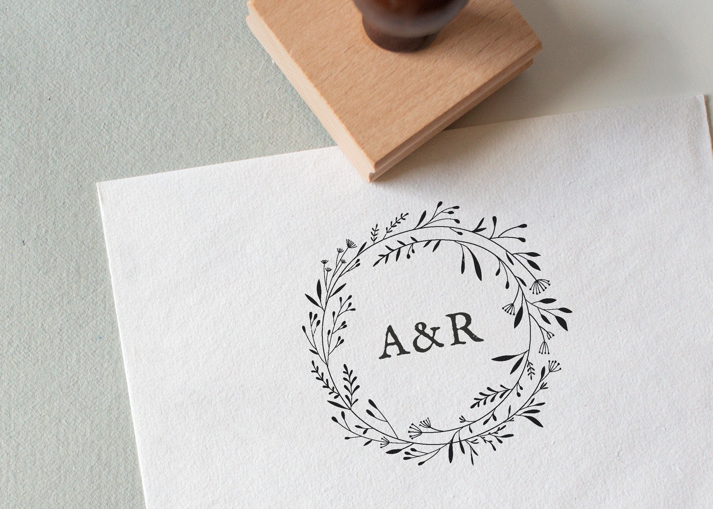 A personalized floral wreath stamp with initials 'AR' in the centre.