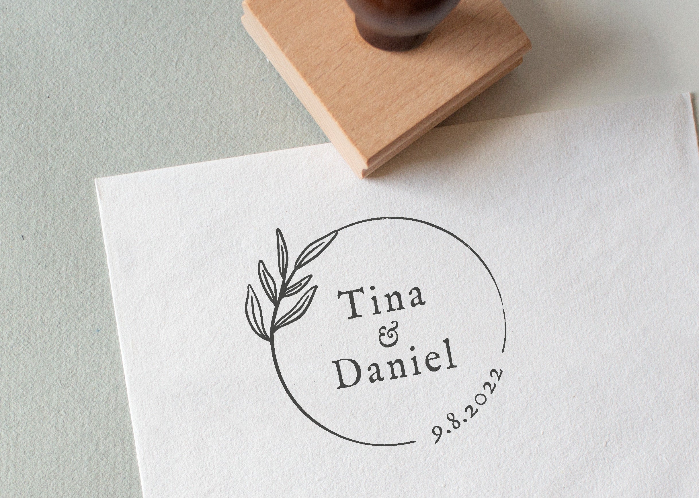 Minimal circle wedding stamp with couple’s names and date, and a beautiful botanical illustration stamped on white textured paper