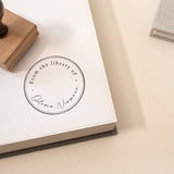 Minimal Script Book Stamp featuring a minimal design of a book stamp with a beautiful script and handwritten font stamped onto the pages of a book