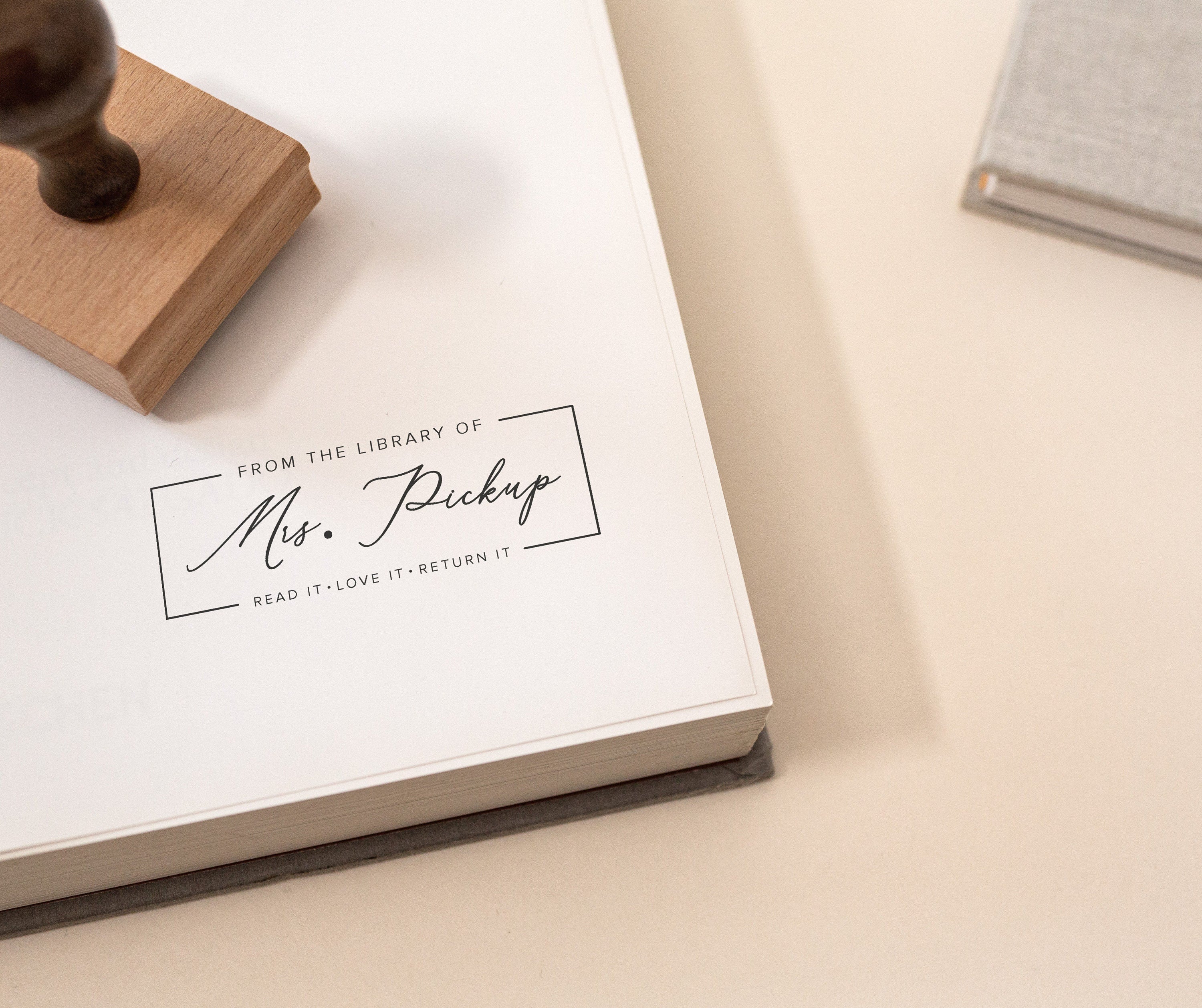 rubber stamp featuring the wording 'from the library of' followed by a teachers name and the wording 'read it, love it, return it' underneath the name. 