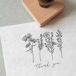 A custom floral-themed rubber stamp with the words 'Thank You' stamped on a piece of paper, accompanied by a wooden rubber stamp
